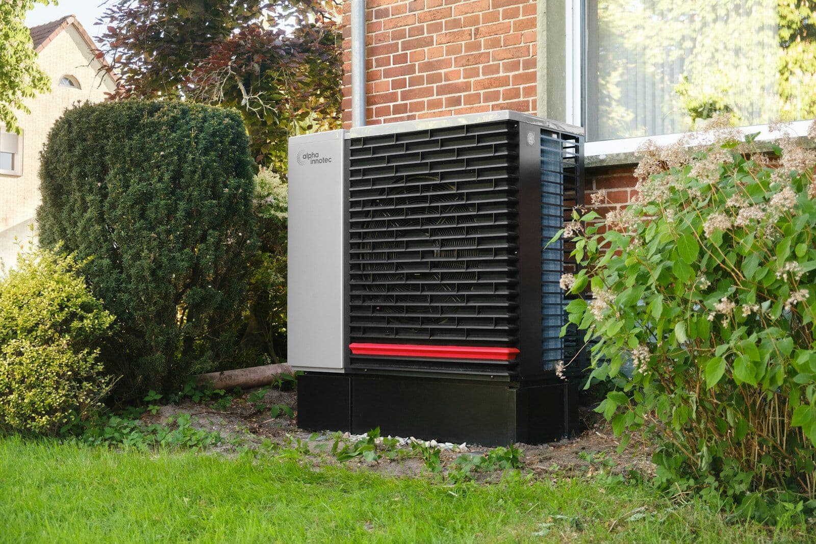Pompe à chaleur air/eau installée dans le jardin d'une maison en brique
